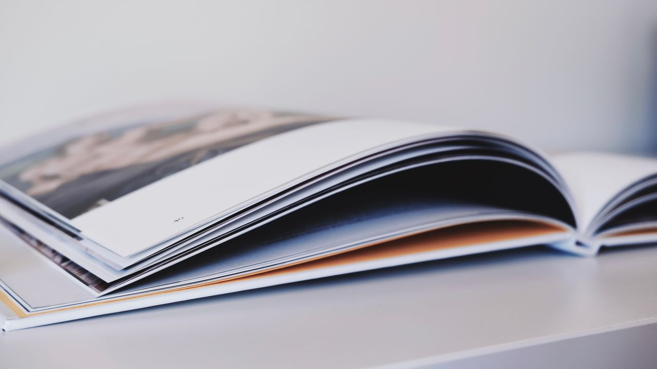 about-us Close-up of an open magazine lying on a white surface, showcasing glossy pages.